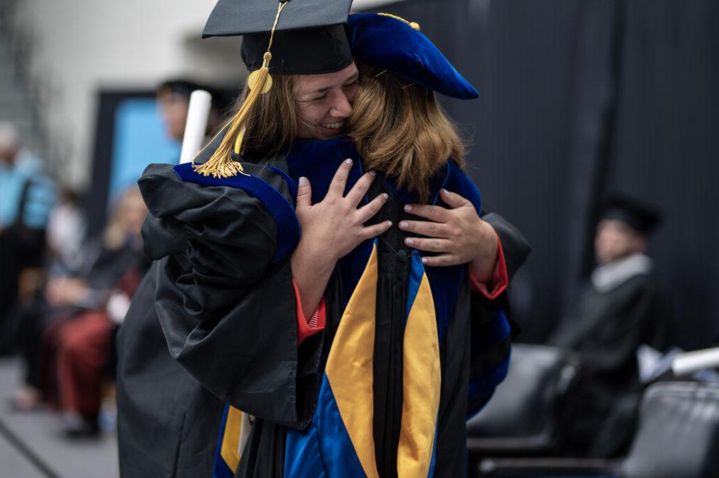 总统博士. 娜塔莉·哈德在毕业典礼上拥抱一名学生.